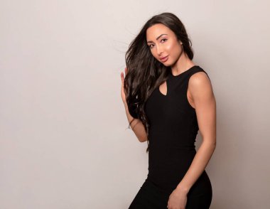 Gri arka planda uzun siyah saçlı ve doğal makyajlı güzel bir kadın. 