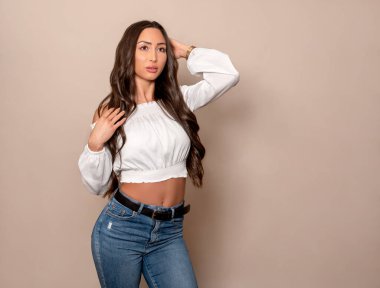 Gri arka planda uzun siyah saçlı ve doğal makyajlı güzel bir kadın. 