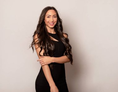 Gri arka planda uzun siyah saçlı ve doğal makyajlı güzel bir kadın. 