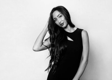 Gri arka planda uzun siyah saçlı ve doğal makyajlı güzel bir kadın. 