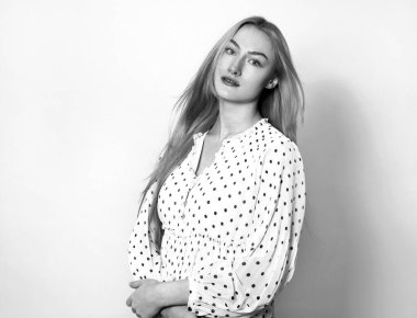 Sarışın, uzun, parlak ve sağlıklı saçları olan, gri arka planda poz veren güzel bir genç kadın.