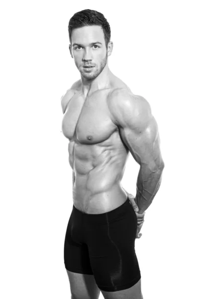 Handsome young bodybuilder showing of his fit body and muscles on isolated background — Stock Photo, Image