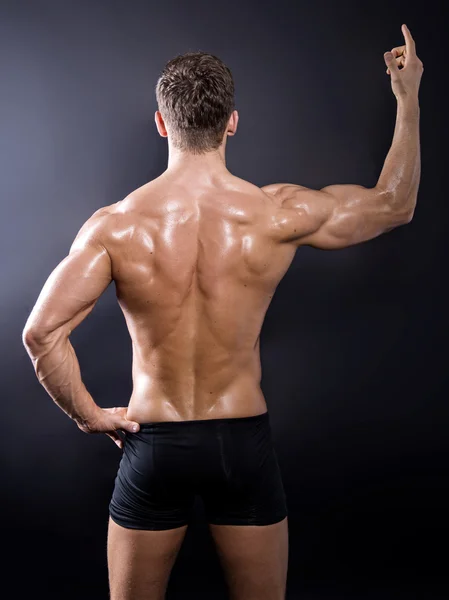 Bonito jovem fisiculturista mostrando de seu corpo apto e músculos — Fotografia de Stock