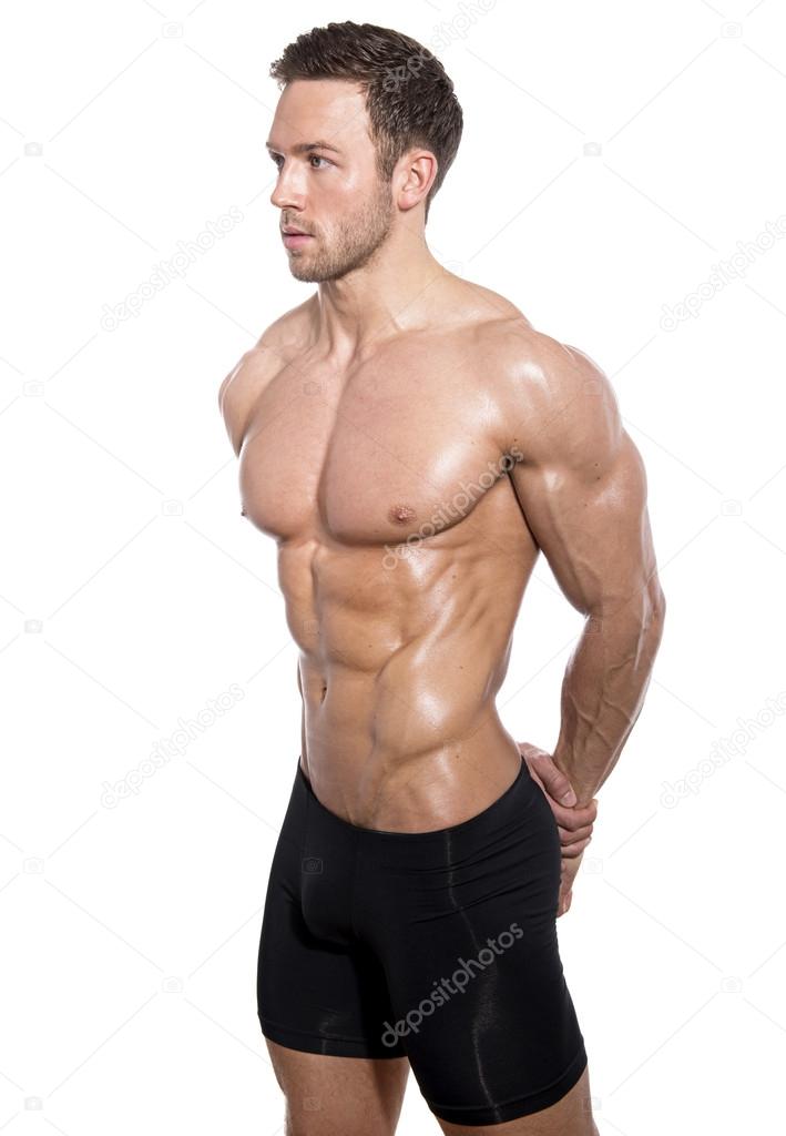 Handsome young bodybuilder showing of his fit body and muscles on isolated background