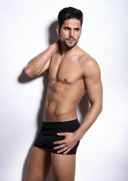 Onun kas gösterilen yakışıklı kaslı genç vücut geliştirmeci