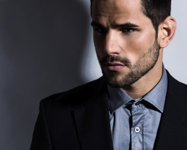 Gri arka planda takım elbiseli yakışıklı bir genç. İş adamı