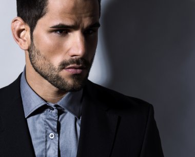 Gri arka planda takım elbiseli yakışıklı bir genç. İş adamı