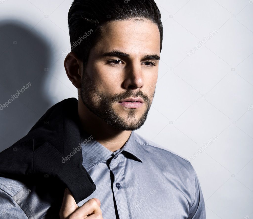 handsome young man in suit on grey background