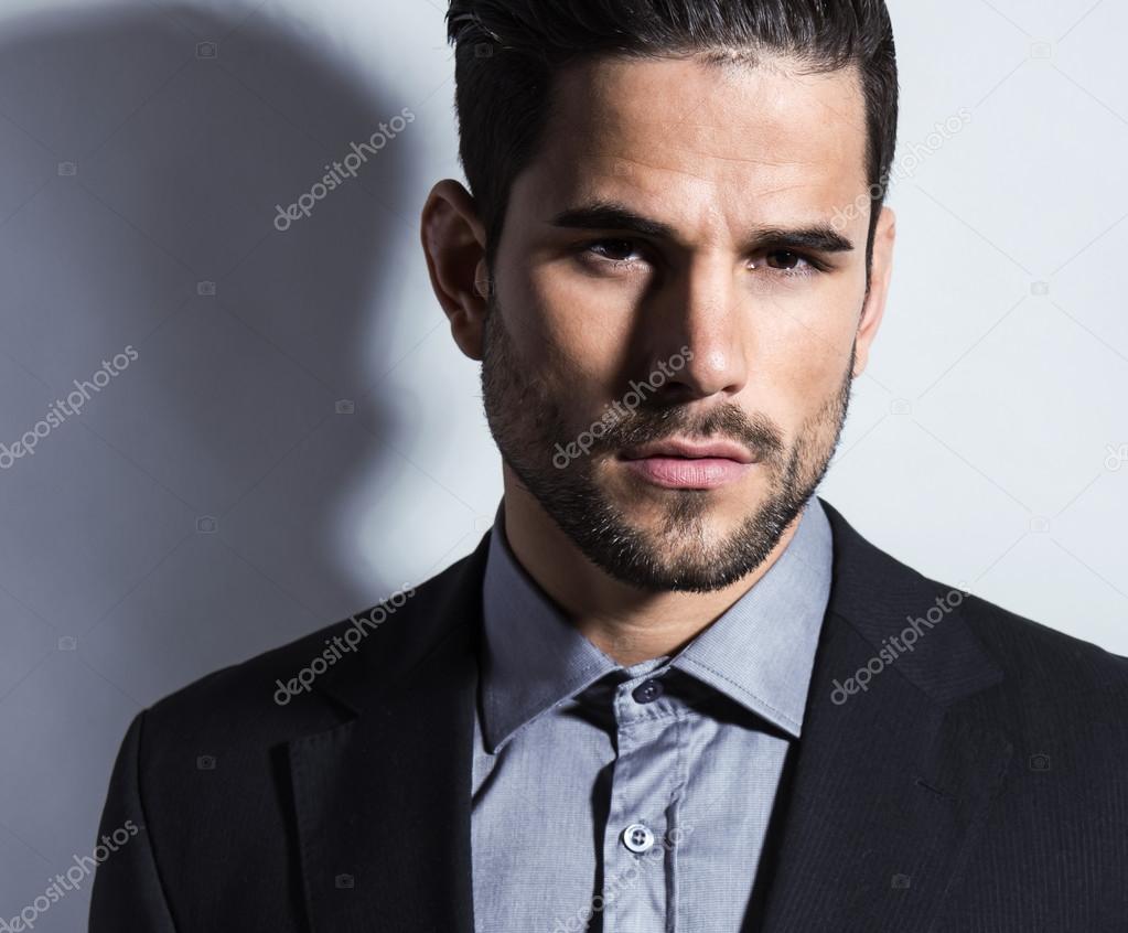 handsome young man in suit on grey background