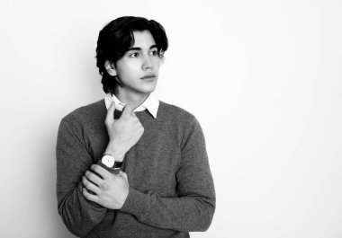 Metal kol saati takan, şık, rahat giyimli yakışıklı bir genç.