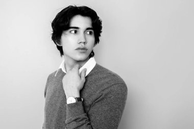 Metal kol saati takan, şık, rahat giyimli yakışıklı bir genç.