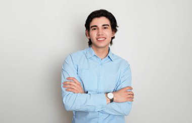 Metal kol saati takan, şık, rahat giyimli yakışıklı bir genç.