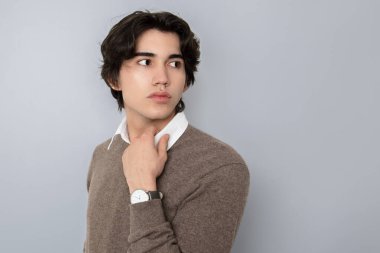 Metal kol saati takan, şık, rahat giyimli yakışıklı bir genç.