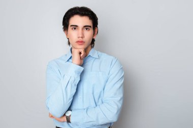 Metal kol saati takan, şık, rahat giyimli yakışıklı bir genç.