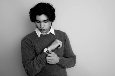 Metal kol saati takan, şık, rahat giyimli yakışıklı bir genç.