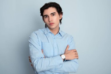Metal kol saati takan, şık, rahat giyimli yakışıklı bir genç.
