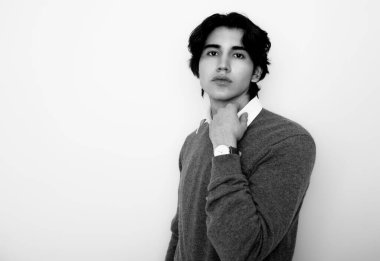 Metal kol saati takan, şık, rahat giyimli yakışıklı bir genç.