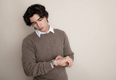 Metal kol saati takan, şık, rahat giyimli yakışıklı bir genç.