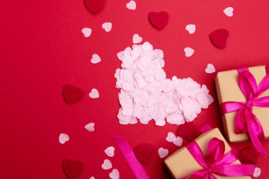 Sevgililer günü ya da yıldönümü kutlamaları için pembe hediye ve kırmızı kurdeleli güller ve kopyalama alanı ile güzel ve şenlikli bir arka plan.