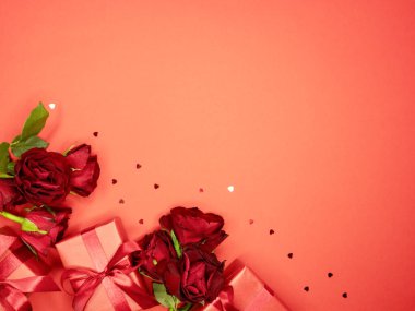 Sevgililer günü ya da yıldönümü kutlamaları için pembe hediye ve kırmızı kurdeleli güller ve kopyalama alanı ile güzel ve şenlikli bir arka plan.