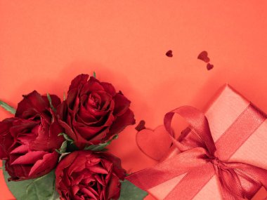 Sevgililer günü ya da yıldönümü kutlamaları için pembe hediye ve kırmızı kurdeleli güller ve kopyalama alanı ile güzel ve şenlikli bir arka plan.