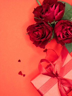 Sevgililer günü ya da yıldönümü kutlamaları için pembe hediye ve kırmızı kurdeleli güller ve kopyalama alanı ile güzel ve şenlikli bir arka plan.