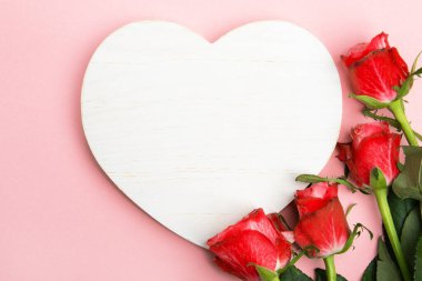 Sevgililer günü, doğum günü ya da yıldönümü kutlamaları için güzel ve şenlikli bir geçmiş. Kırmızı güller ve yazı için beyaz kalp şeklinde bir kart.
