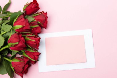 Sevgililer günü, doğum günü ya da yıldönümü kutlamaları için güzel ve şenlikli bir geçmiş. Kırmızı güller ve yazı için beyaz kalp şeklinde bir kart.