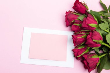 Sevgililer günü, doğum günü ya da yıldönümü kutlamaları için güzel ve şenlikli bir geçmiş. Kırmızı güller ve yazı için beyaz kalp şeklinde bir kart.