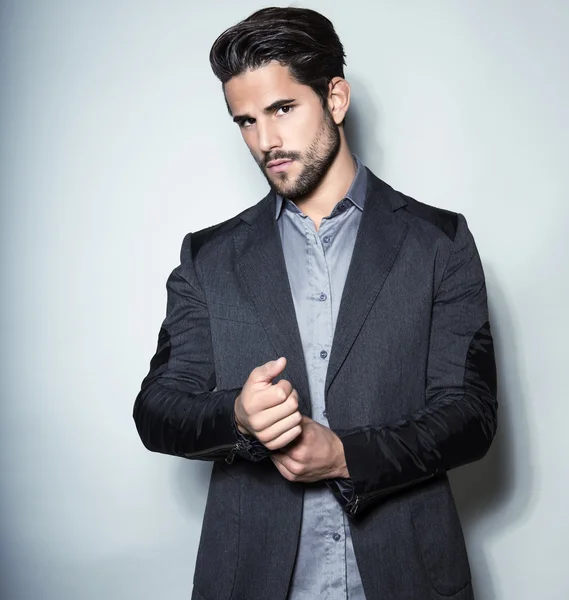 Schöner junger Mann im Anzug auf grauem Hintergrund — Stockfoto
