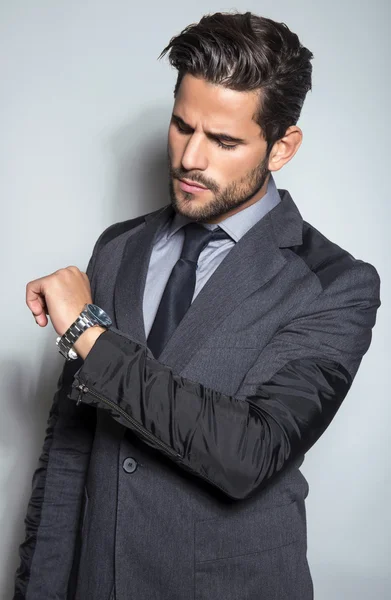 Schöner junger Mann im Anzug auf grauem Hintergrund — Stockfoto
