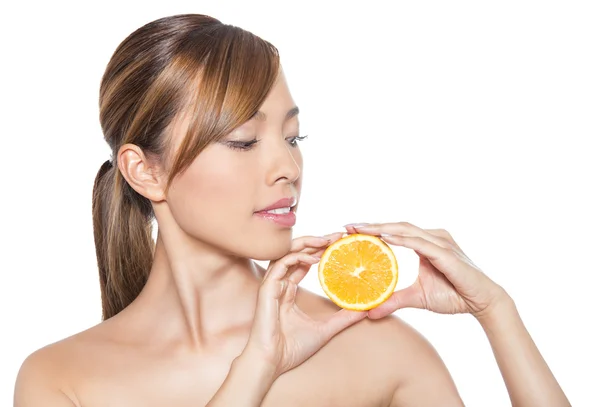 Beautiful young asian woman with long hair, flawless skin and perfect make-up, holding orange — Stock Photo, Image