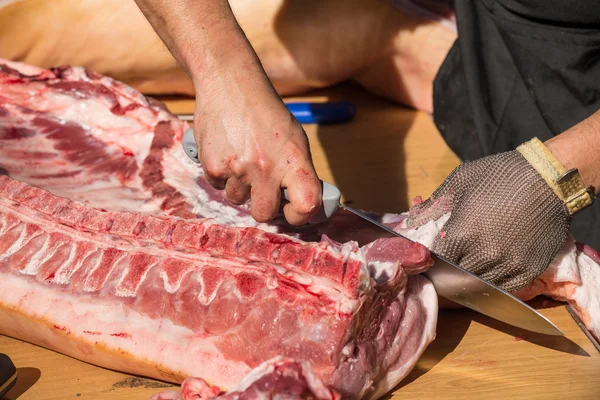 Slager handen op vers varkensvlees — Stockfoto