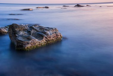 Gün batımında deniz manzarası. Taşlar ve kayalarla dolu uzun bir kepenk..