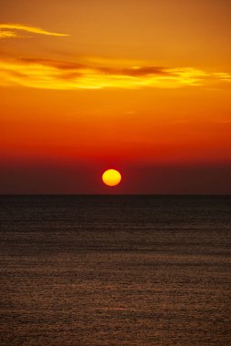 Gün batımında deniz manzarası. Güneşin kırmızı diski ufkun ötesinde..