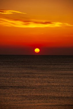 Gün batımında deniz manzarası. Güneşin kırmızı diski ufkun ötesinde..