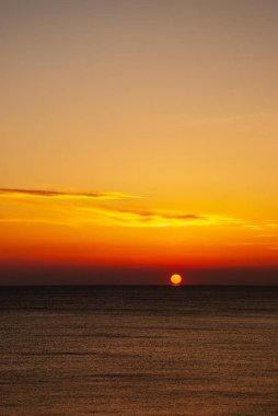 Gün batımında deniz manzarası. Güneşin kırmızı diski ufkun ötesinde..