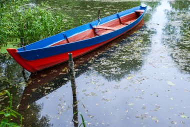 Sahilde küçük bir nehrin kanalında, çimenler ve ağaçlarla çevrili tekneler..