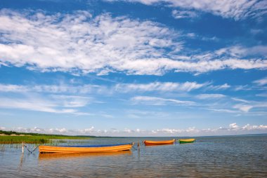 Gölde tekneleri ve beyaz bulutlu mavi gökyüzü olan güzel bir manzara..