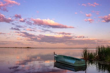 Gölde tekneleri ve gün batımında bulutları olan güzel bir manzara..