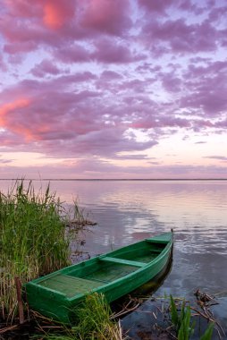 Gölde tekneleri ve gün batımında bulutları olan güzel bir manzara..