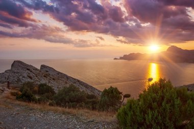 Sudak, Kırım - Cape Meganom 'un manzarası. Güzel bulutlu gün batımı gökyüzü. Karadeniz ve Kırım dağlarının sırtı akşam güneşinin altında..