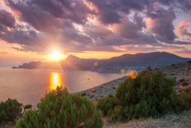 Sudak, Kırım - Cape Meganom 'un manzarası. Güzel bulutlu gün batımı gökyüzü. Karadeniz ve Kırım dağlarının sırtı akşam güneşinin altında..