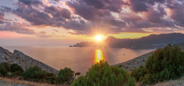 Sudak, Kırım - Cape Meganom 'un manzarası. Güzel bulutlu gün batımı gökyüzü. Karadeniz ve Kırım dağlarının tepeleri akşam güneşinin altında. Panorama.