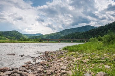 Sibirya 'nın manzarası. Kiya Nehri, dağ kıyıları ve Kemerovo bölgesindeki yeşil ormanlar. Mavi gökyüzü ve bulutlu gündüz manzarası.