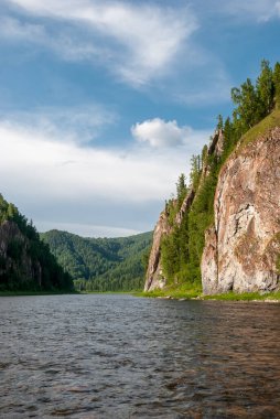 Sibirya 'nın manzarası. Kiya Nehri, dağ kıyıları ve Kemerovo bölgesindeki yeşil ormanlar. Mavi gökyüzü ve bulutlu gündüz manzarası.