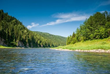 Sibirya 'nın manzarası. Kiya Nehri, dağ kıyıları ve Kemerovo bölgesindeki yeşil ormanlar. Mavi gökyüzü ve bulutlu gündüz manzarası.
