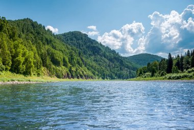 Sibirya 'nın manzarası. Kiya Nehri, dağ kıyıları ve Kemerovo bölgesindeki yeşil ormanlar. Mavi gökyüzü ve bulutlu gündüz manzarası.
