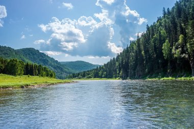 Sibirya 'nın manzarası. Kiya Nehri, dağ kıyıları ve Kemerovo bölgesindeki yeşil ormanlar. Mavi gökyüzü ve bulutlu gündüz manzarası.