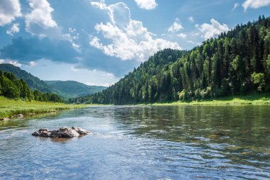 Sibirya 'nın manzarası. Kiya Nehri, dağ kıyıları ve Kemerovo bölgesindeki yeşil ormanlar. Mavi gökyüzü ve bulutlu gündüz manzarası.